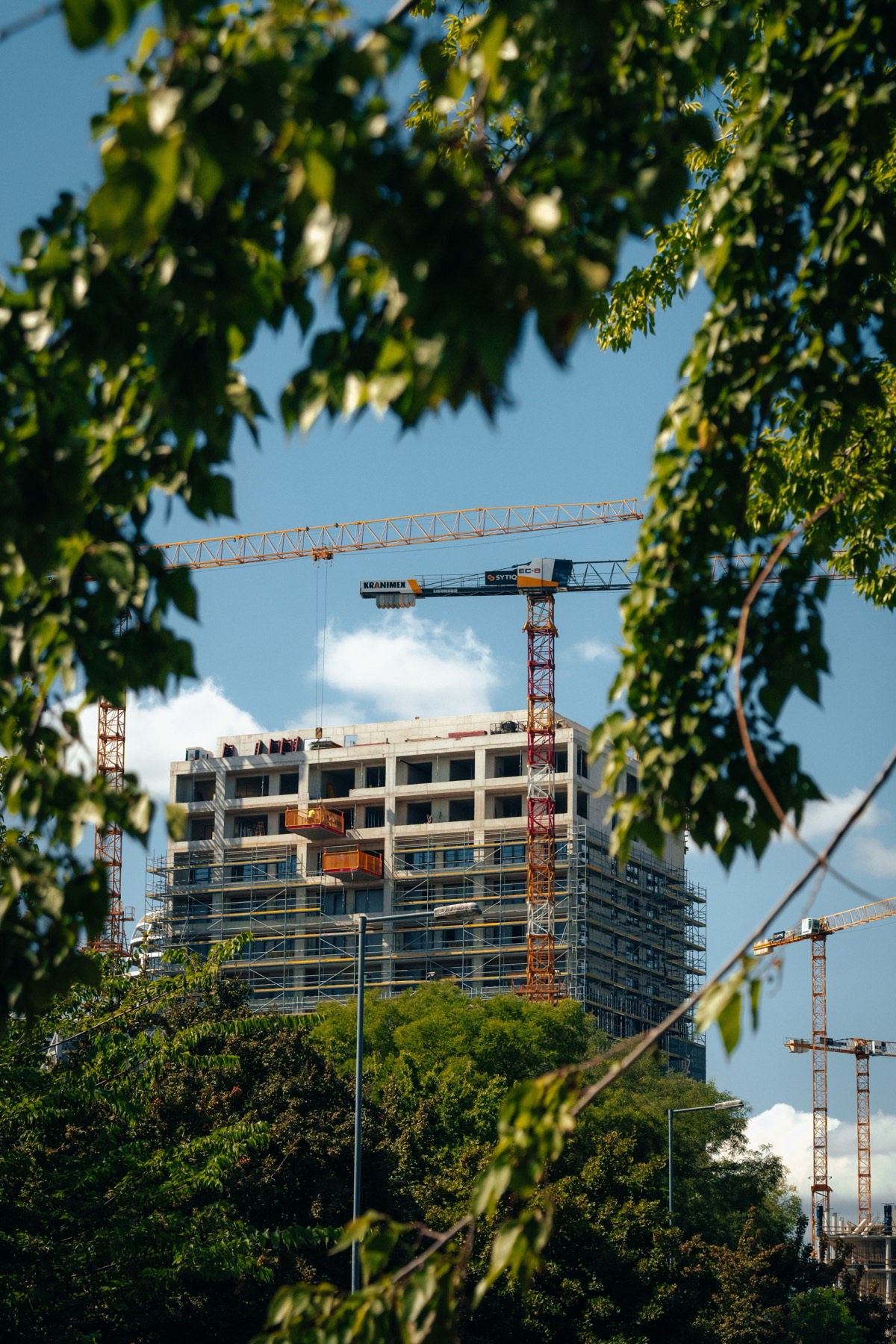 Kran über einem eingerüsteten Rohbau